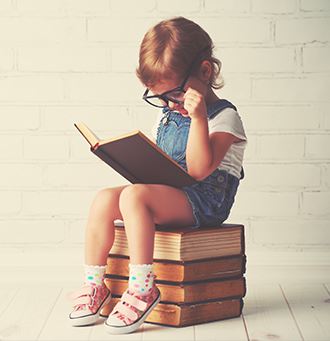 Little girl reading sitting on some books